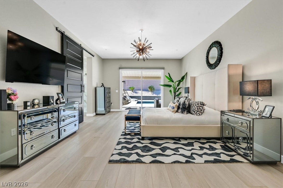 2689 Pioneer Estates Court, Las Vegas, NV 89117 A spacious bedroom boasts light wood floors and sliding glass doors opening to the pool.