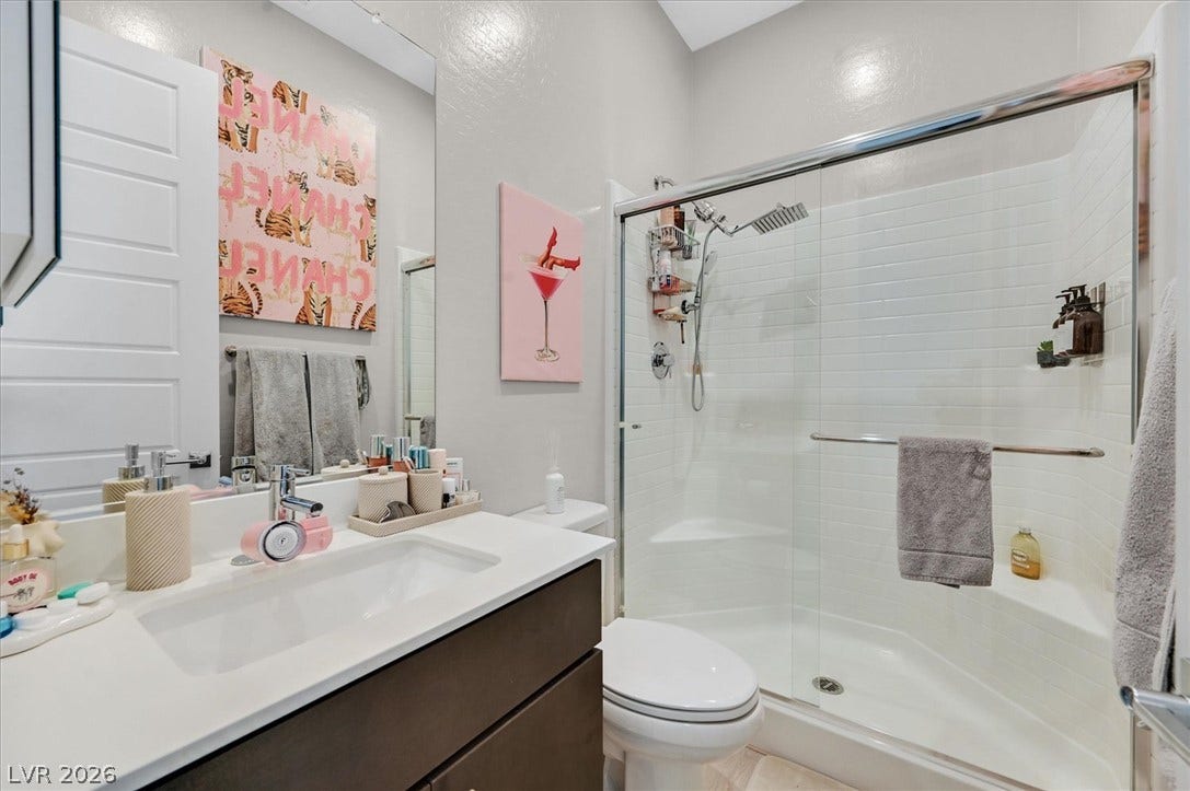 2689 Pioneer Estates Court, Las Vegas, NV 89117 A glass-enclosed shower with subway tile sits adjacent to a modern vanity.
