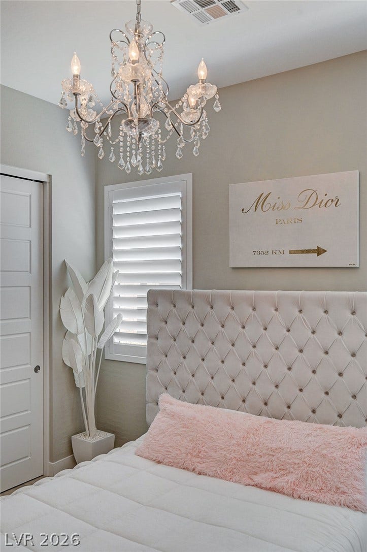 2689 Pioneer Estates Court, Las Vegas, NV 89117 An elegant crystal chandelier hangs above this cozy bedroom space featuring a plantation shuttered window.