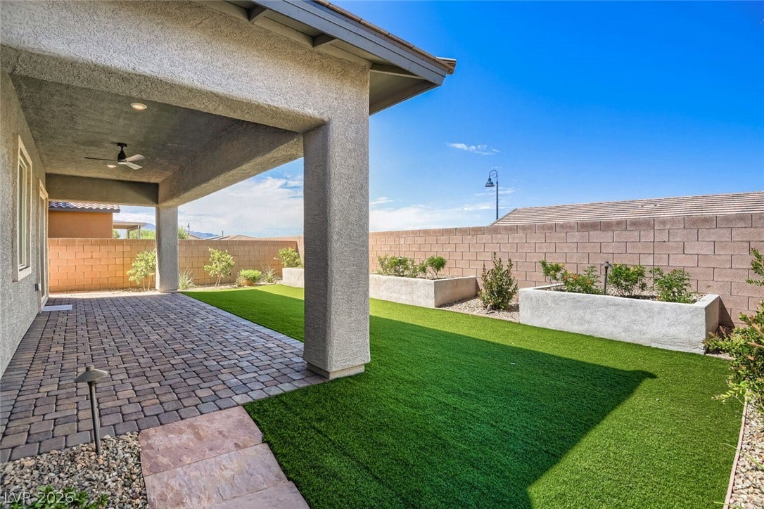 647 Longfeather Street, Henderson, NV 89011 A spacious covered patio with stone pavers overlooks a neat backyard and raised garden beds.