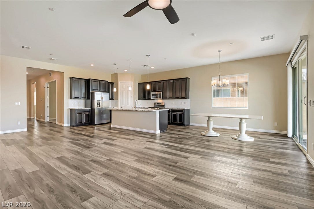 647 Longfeather Street, Henderson, NV 89011 Gleaming wood-look floors anchor a sprawling, open-concept layout connecting the kitchen and dining zones.