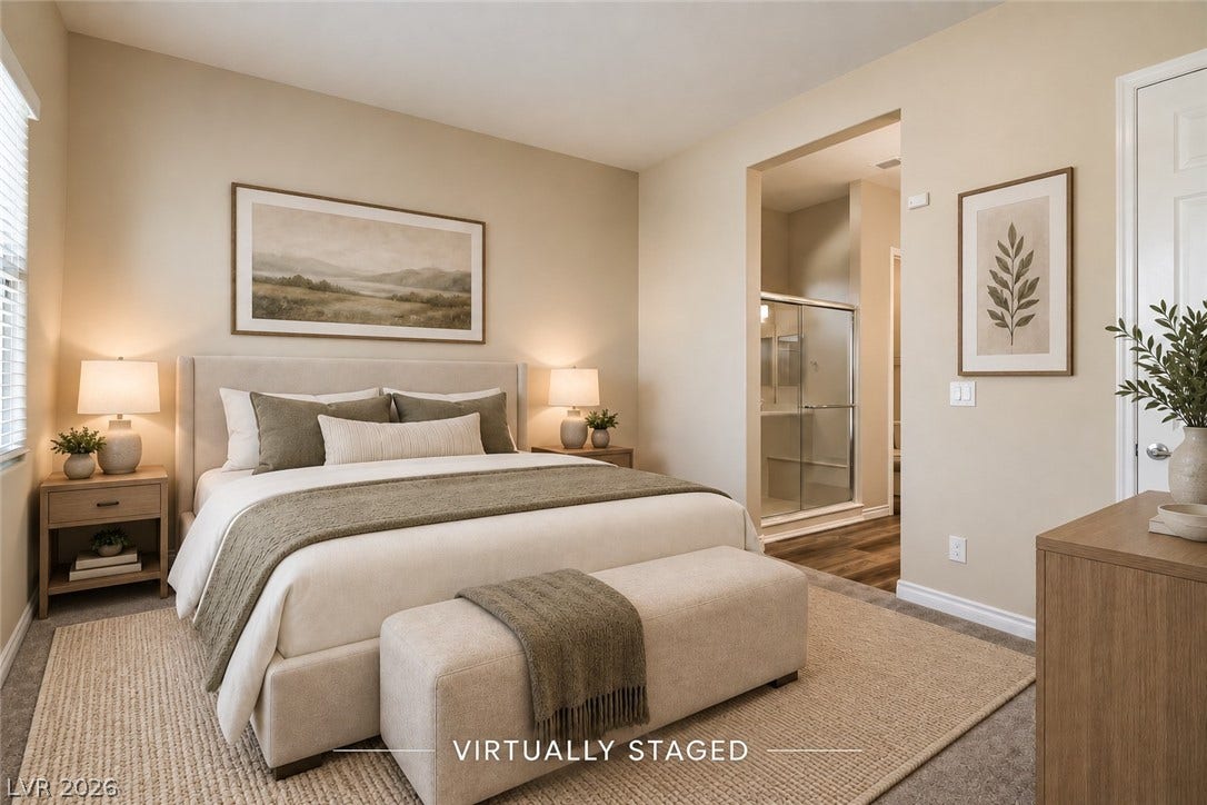 647 Longfeather Street, Henderson, NV 89011 A spacious bedroom features direct access to an en suite bathroom and plush carpeted flooring.