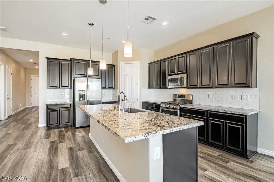 647 Longfeather Street, Henderson, NV 89011 Rich dark cabinetry and expansive granite countertops anchor this beautifully appointed modern kitchen.