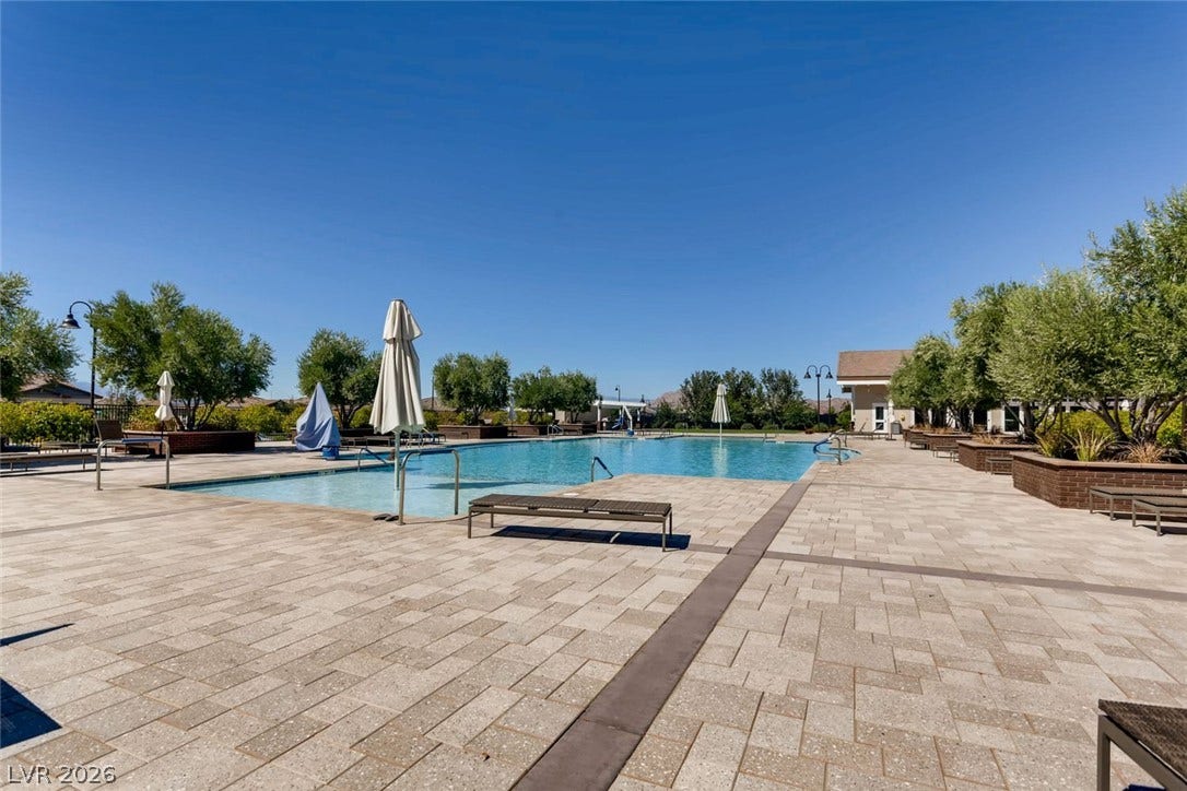 647 Longfeather Street, Henderson, NV 89011 An expansive paved terrace surrounds the sparkling community swimming pool under clear blue skies.