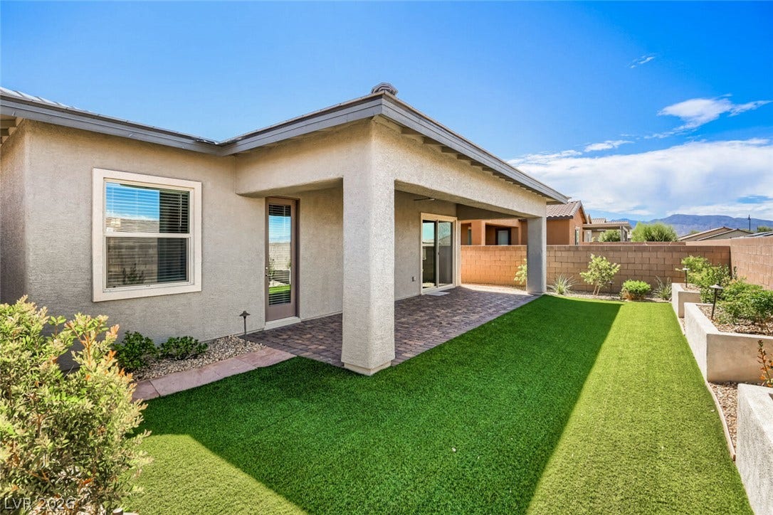 647 Longfeather Street, Henderson, NV 89011 An inviting covered patio overlooks a manicured green lawn and textured block privacy walls.