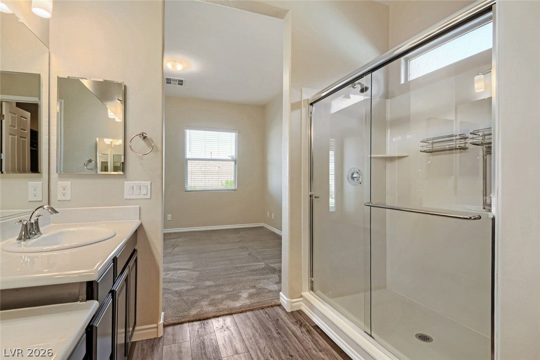 647 Longfeather Street, Henderson, NV 89011 A modern bathroom features a glass-enclosed shower alongside wood-look flooring.