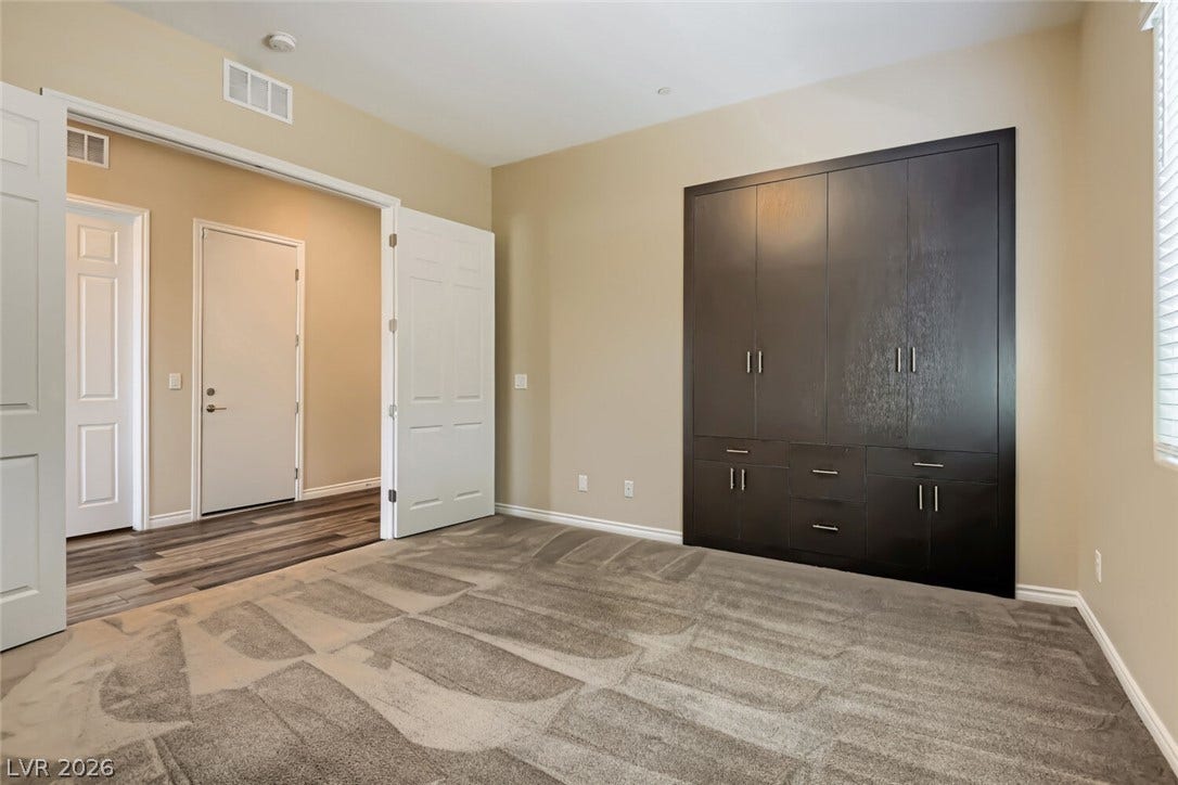 647 Longfeather Street, Henderson, NV 89011 Plush carpeting and integrated custom cabinetry define this versatile bedroom space.
