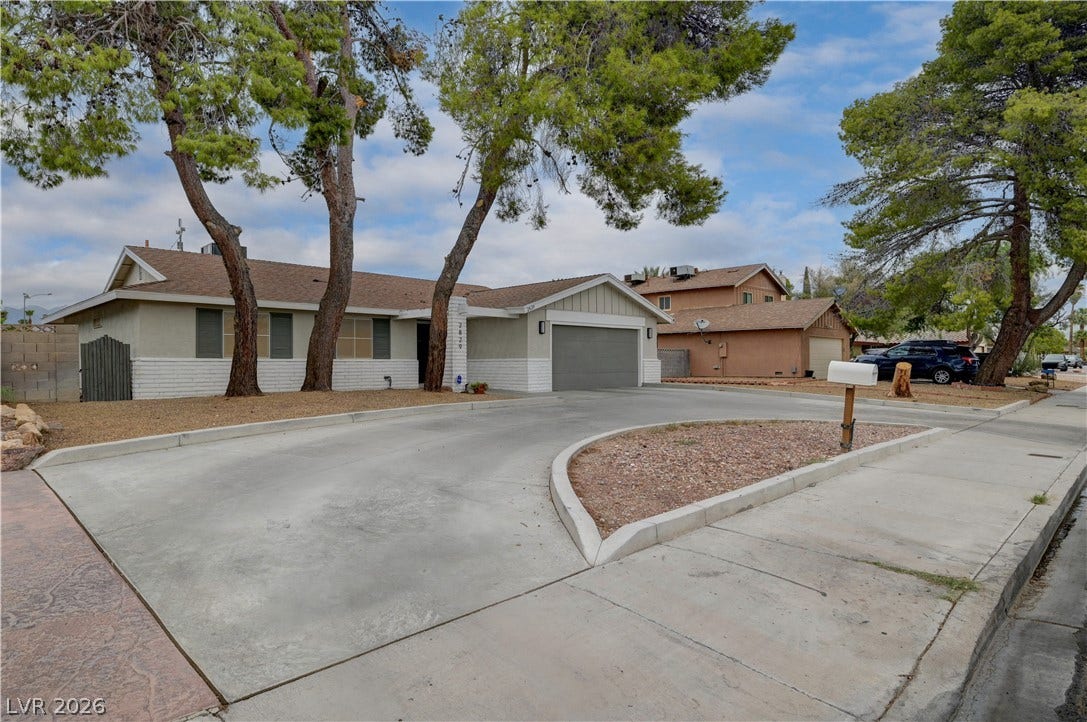 2829 N Michael Way, Las Vegas, NV 89108 Mature trees shade a clean concrete driveway leading to a classic single-story suburban residence.