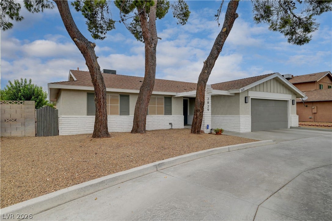 2829 N Michael Way, Las Vegas, NV 89108 Mature trees frame the classic facade of this single-story home with a clean concrete driveway.