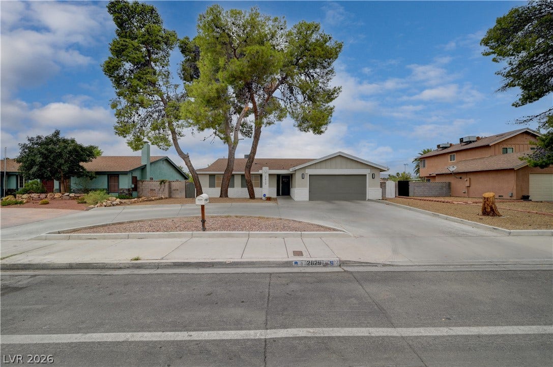 2829 N Michael Way, Las Vegas, NV 89108 Mature trees shade a wide concrete driveway leading to a classic single-story suburban residence.