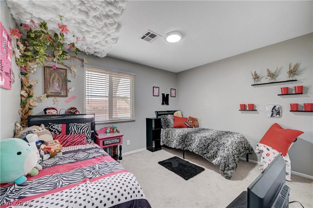 2829 N Michael Way, Las Vegas, NV 89108 Natural light streams through a wide window onto neutral walls and soft carpeting.