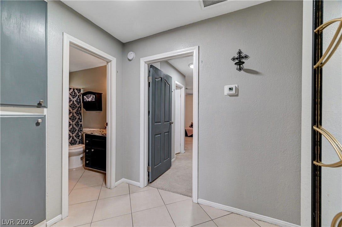 2829 N Michael Way, Las Vegas, NV 89108 Tiled flooring and neutral walls define this central hallway connecting the home's living areas.