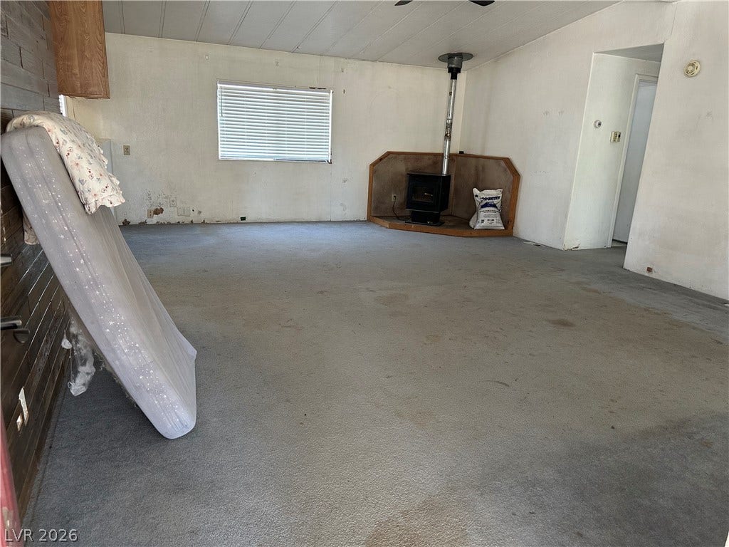 An open living area features carpet flooring and a corner wood stove setup.