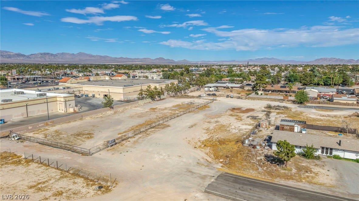 Distant mountain ranges frame a wide view of this expansive commercial lot under clear blue skies.