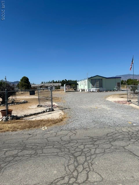 Pahrump, NV 89048 An expansive gravel driveway leads toward a classic manufactured home set against distant mountain views.