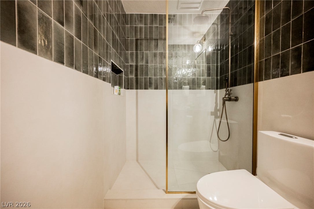 5741 S Pearl Street, Las Vegas, NV 89120 Bold vertical tiling meets a sleek glass walk-in shower in this modern bathroom space.