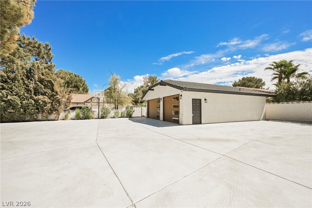 5741 S Pearl Street, Las Vegas, NV 89120 An expansive concrete driveway leads to a detached multi-car garage beneath clear blue skies.