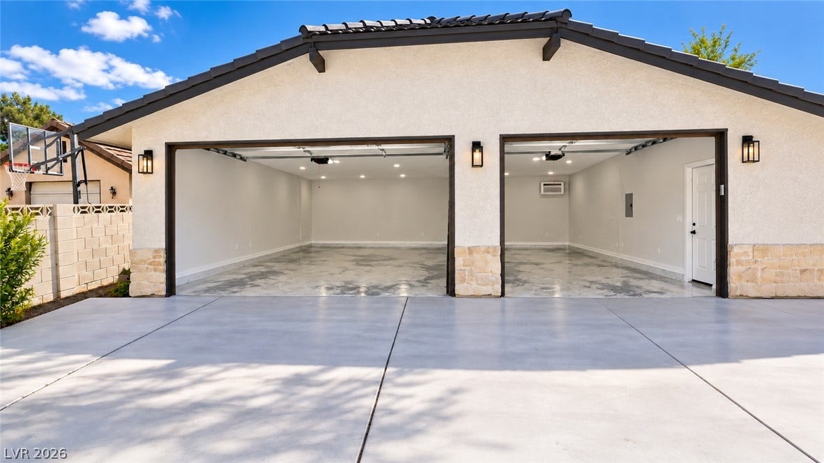 5741 S Pearl Street, Las Vegas, NV 89120 An expansive concrete driveway leads to a modern three-car garage with finished floors and recessed lighting.