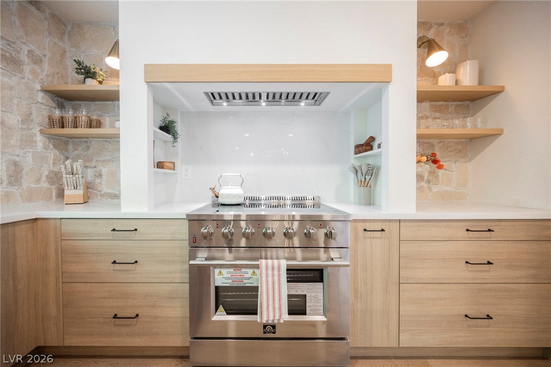 5741 S Pearl Street, Las Vegas, NV 89120 Natural stone accent walls frame a professional gas range nestled under a custom wood-trimmed hood.