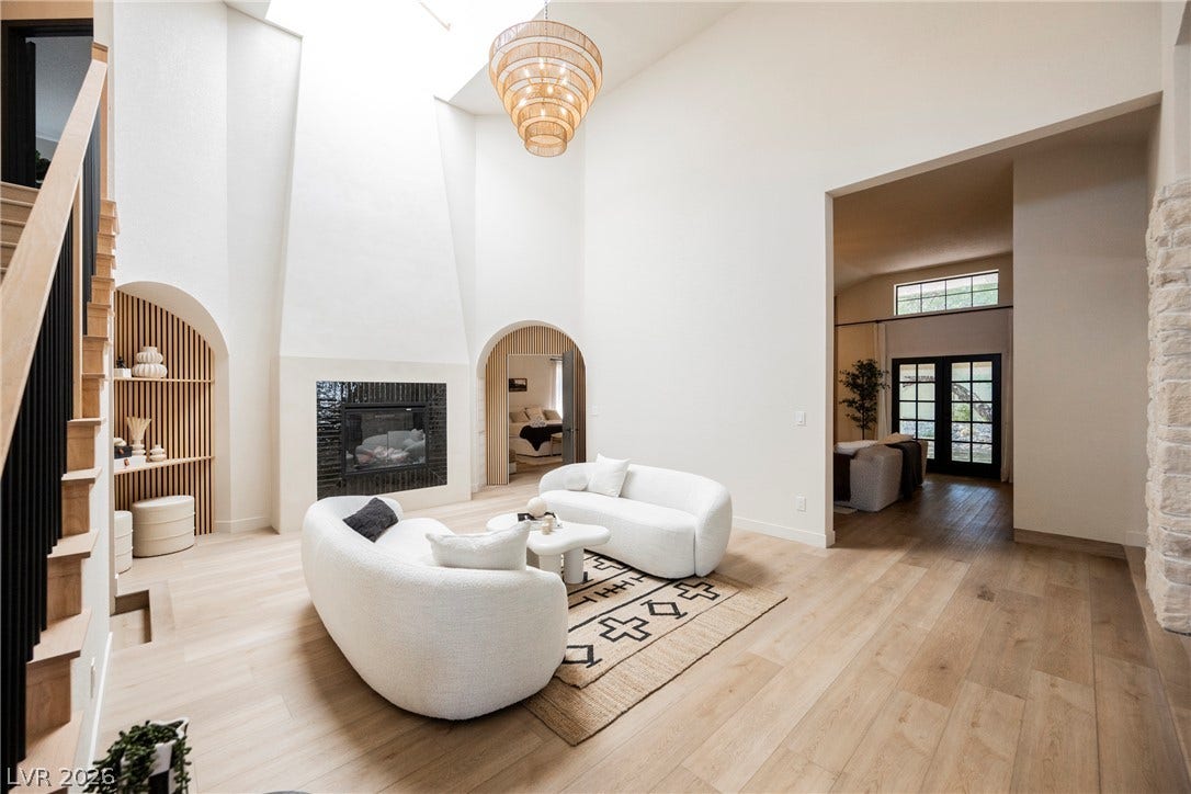 5741 S Pearl Street, Las Vegas, NV 89120 Soaring ceilings, a modern fireplace, and warm wood flooring define this open-concept living space.