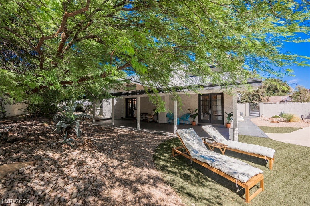 5741 S Pearl Street, Las Vegas, NV 89120 Mature trees shade a covered patio transitioning seamlessly to the landscaped outdoor living space.