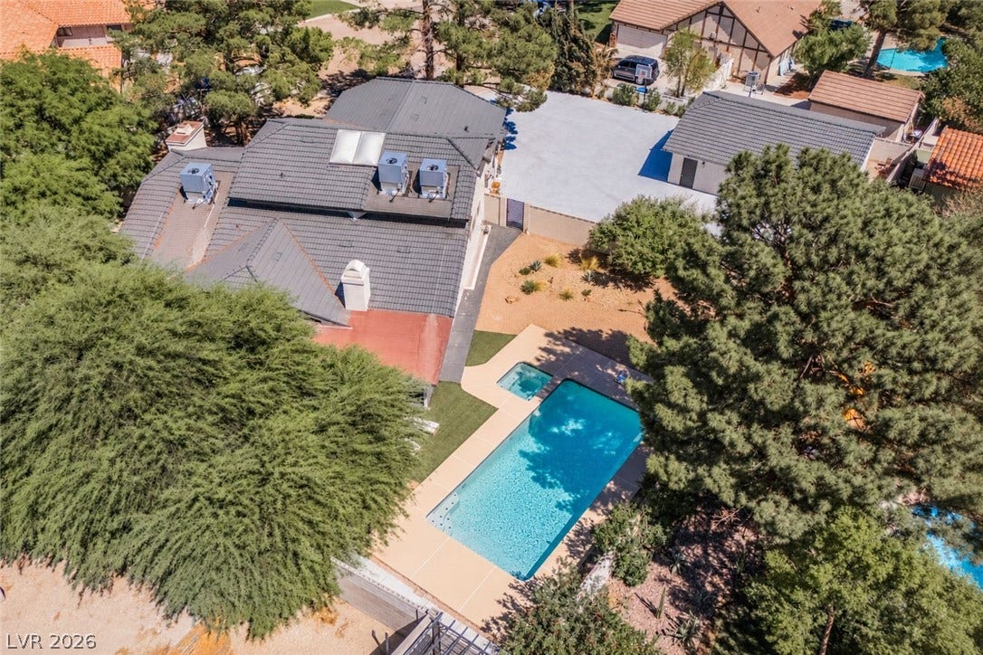 5741 S Pearl Street, Las Vegas, NV 89120 Mature trees frame a sparkling backyard swimming pool and concrete patio area.