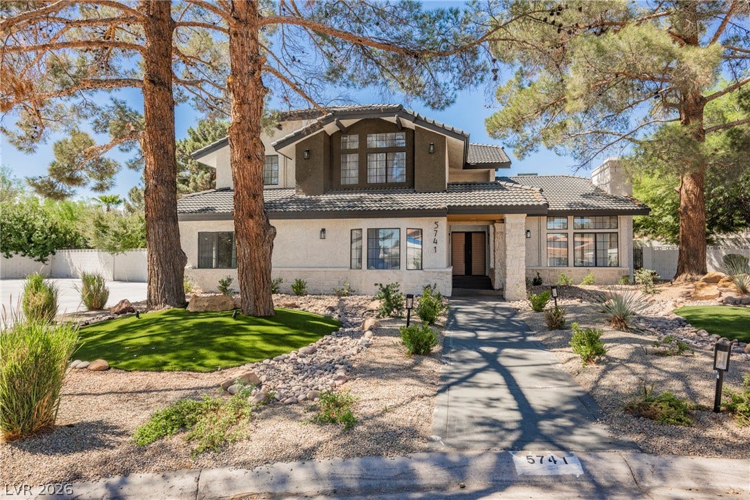 5741 S Pearl Street, Las Vegas, NV 89120 Mature trees shade a paved walkway leading to the entrance of this multi-level home.