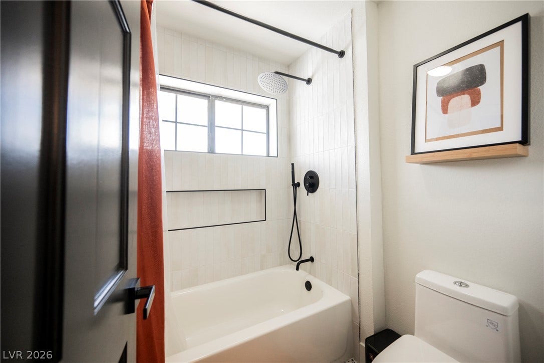 5741 S Pearl Street, Las Vegas, NV 89120 Crisp white vertical tiling surrounds a modern shower and tub combination with matte black fixtures.