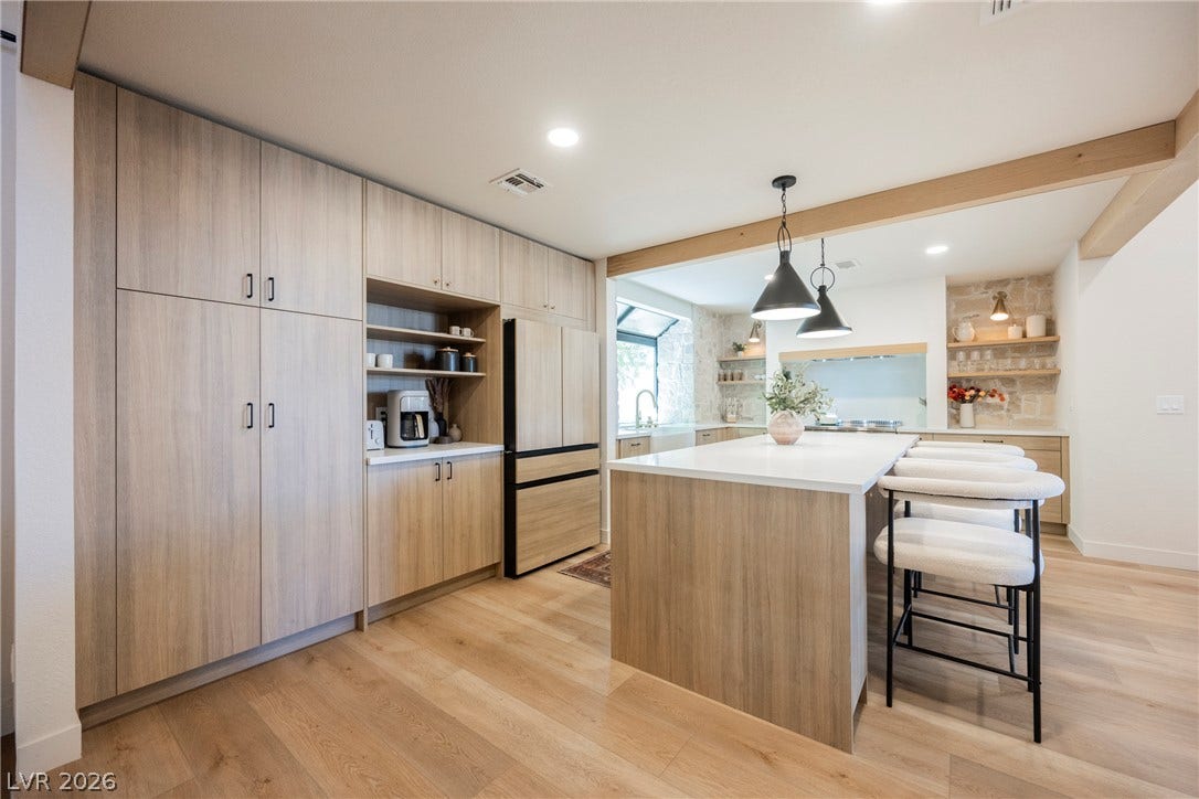 5741 S Pearl Street, Las Vegas, NV 89120 Warm wood floors and modern cabinetry frame this open kitchen space featuring a large central island.