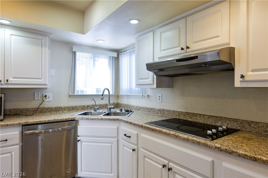 817 Spyglass Lane, Las Vegas, NV 89107 Granite countertops and clean white cabinetry frame a functional cooking space with recessed lighting.