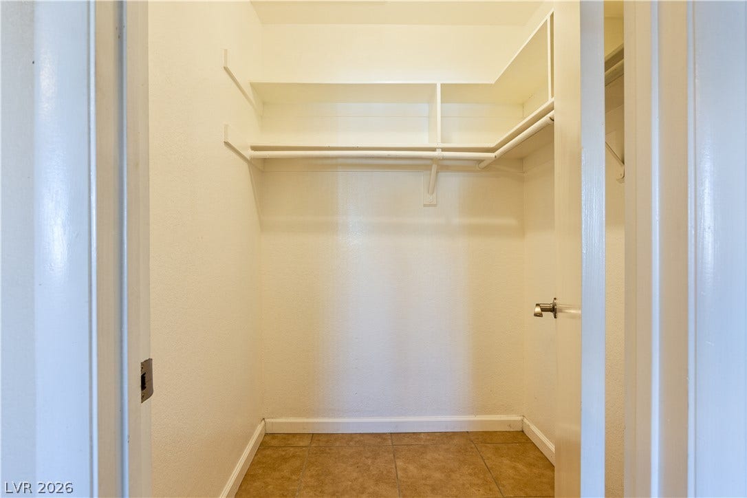 817 Spyglass Lane, Las Vegas, NV 89107 Ample storage space defines this walk-in closet featuring tiled flooring and integrated shelving in the primary Bedroom.