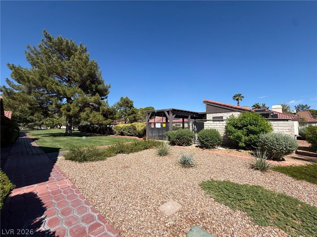 817 Spyglass Lane, Las Vegas, NV 89107 Greenery, gravel beds flank a paved walkway leading through the community grounds.