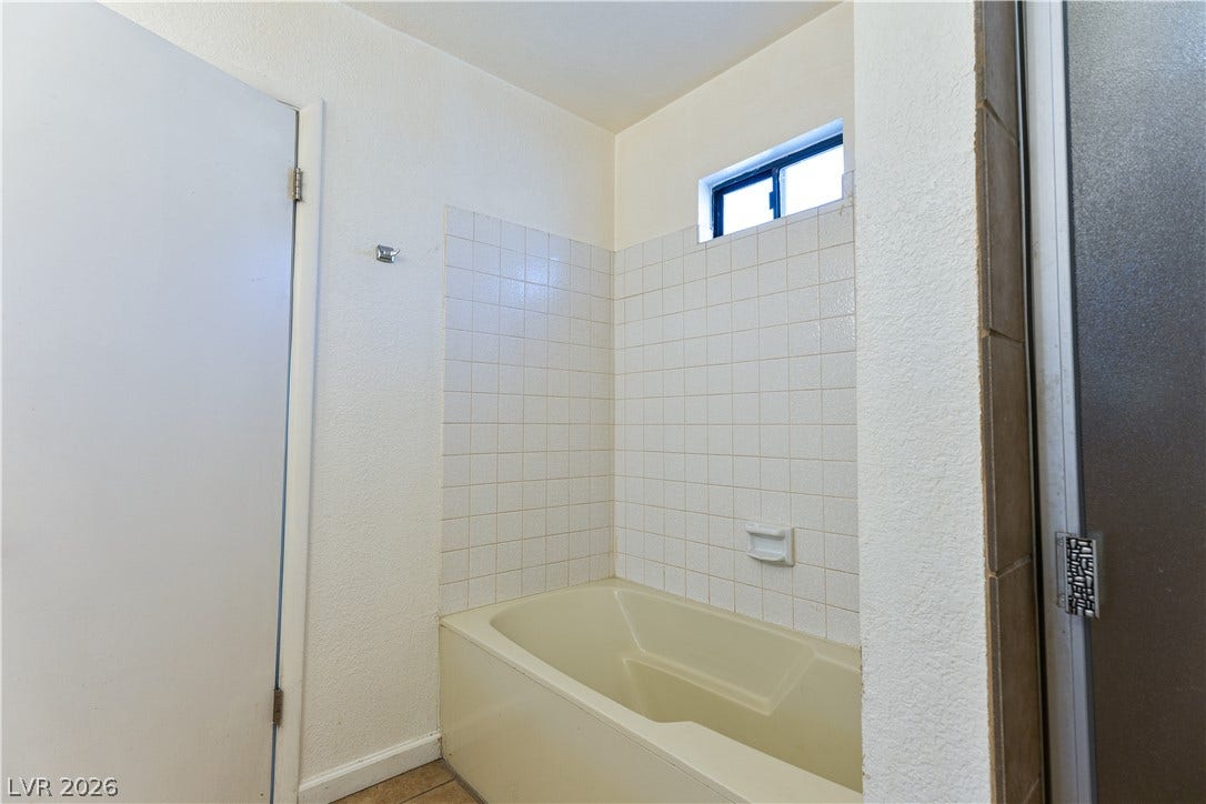 817 Spyglass Lane, Las Vegas, NV 89107 Tiled walls and a high window surround the built-in soaking tub.