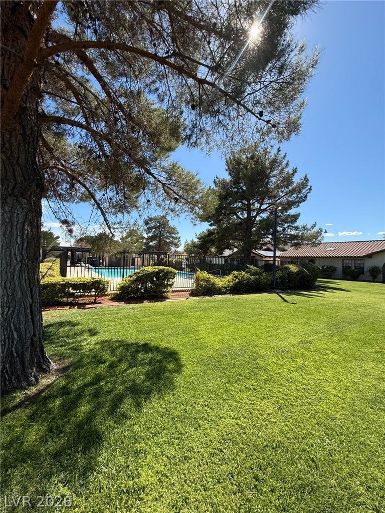 817 Spyglass Lane, Las Vegas, NV 89107 Mature trees shade a manicured lawn leading toward the fenced community pool area.