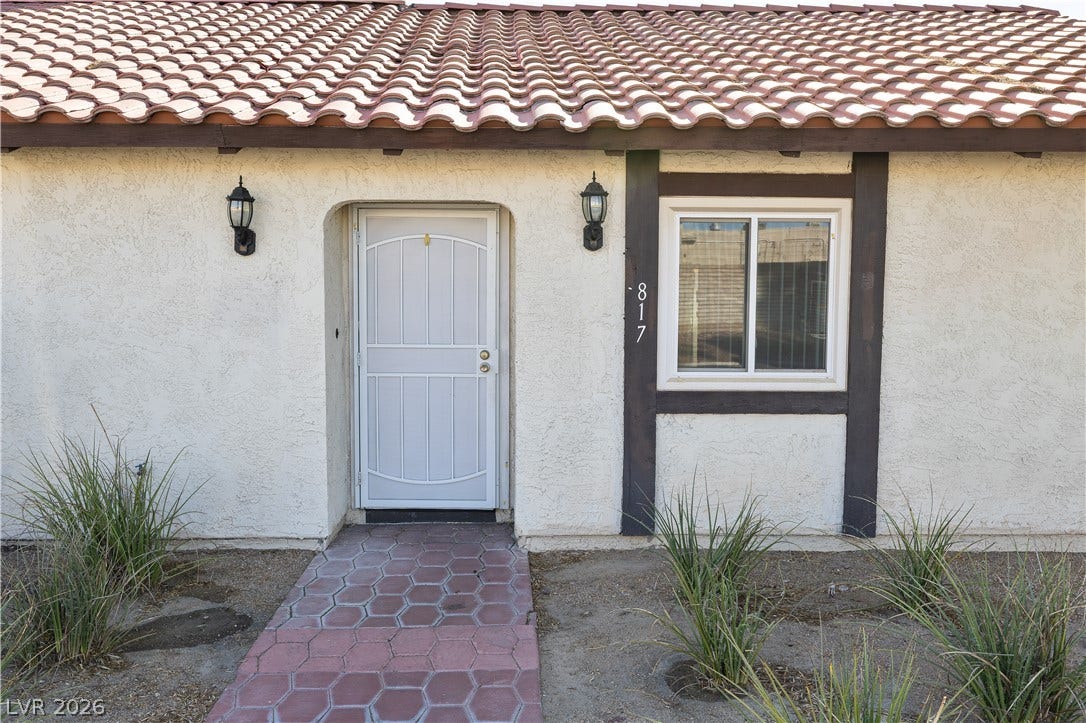 817 Spyglass Lane, Las Vegas, NV 89107 A welcoming front entrance featuring a tiled pathway, textured stucco walls, and spanish tile roofing.
