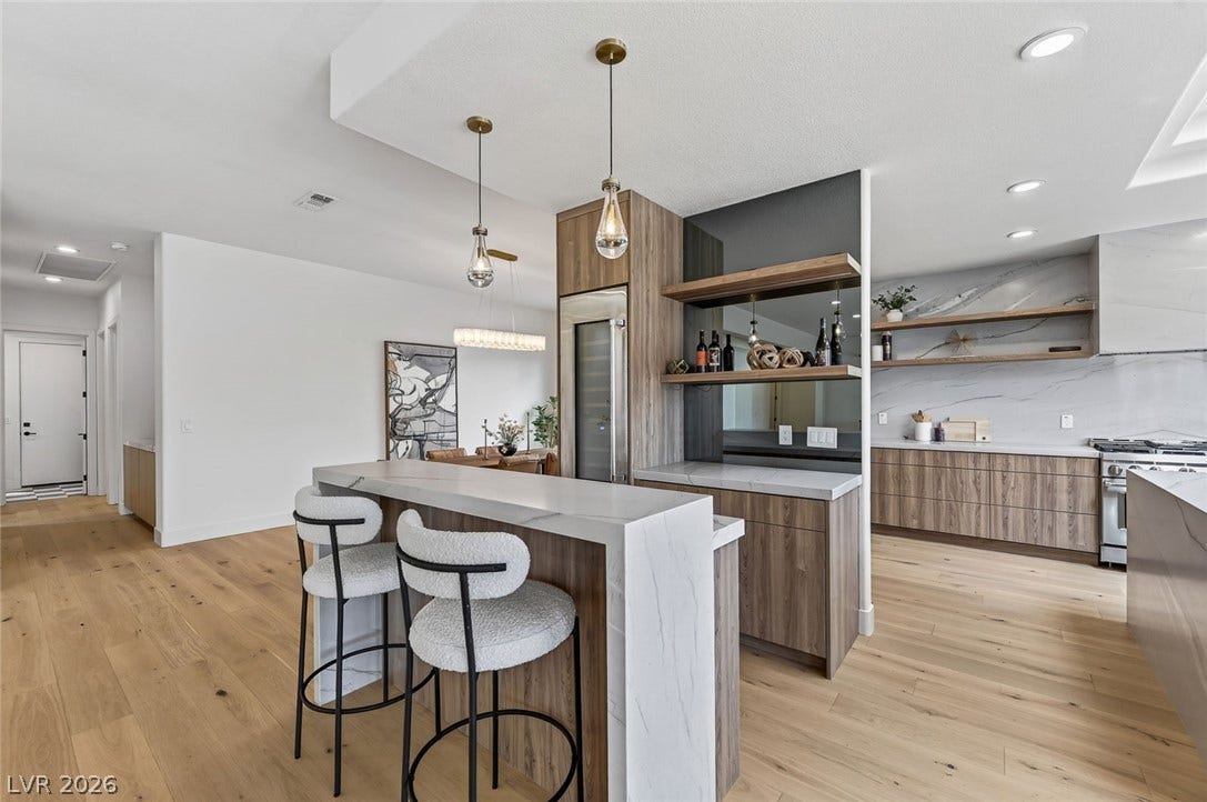 1900 Glenview Drive, Las Vegas, NV 89134 Crisp white walls and warm wood flooring frame a modern open kitchen and bar area.