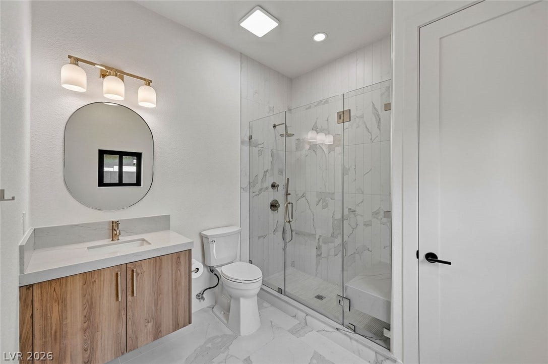 1900 Glenview Drive, Las Vegas, NV 89134 Elegant marble-patterned tile floors and a glass-enclosed shower define this modern bathroom space.