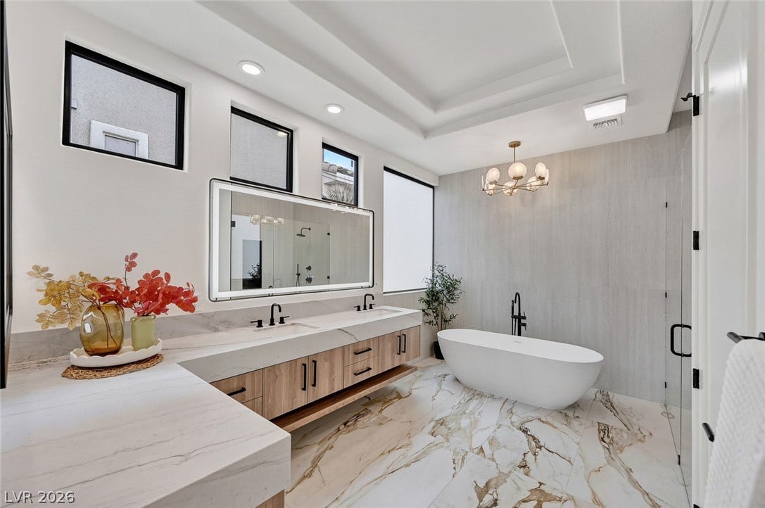 1900 Glenview Drive, Las Vegas, NV 89134 Elegance defines this space featuring a dual vanity, marble-patterned flooring, and a freestanding tub.