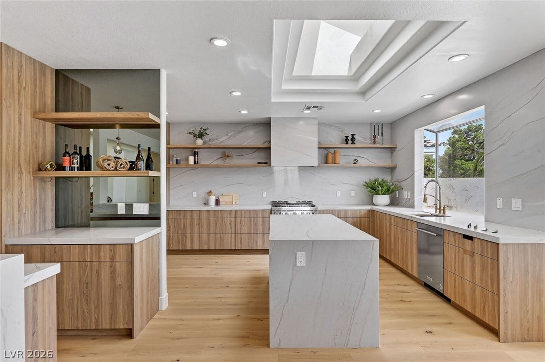 1900 Glenview Drive, Las Vegas, NV 89134 Rich wood cabinetry paired with waterfall stone countertops anchors this airy, modern culinary space.