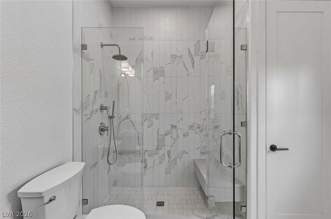 1900 Glenview Drive, Las Vegas, NV 89134 Floor-to-ceiling tilework and seamless glass paneling elevate this modern walk-in shower.