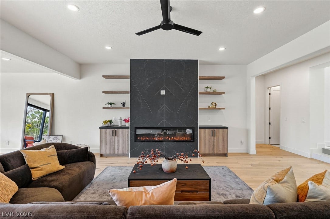 1900 Glenview Drive, Las Vegas, NV 89134 A modern fireplace is flanked by built-in shelving over light-toned hardwood flooring.