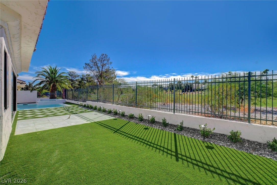 1900 Glenview Drive, Las Vegas, NV 89134 A manicured backyard lawn meets a modern perimeter fence overlooking scenic golf course greens.