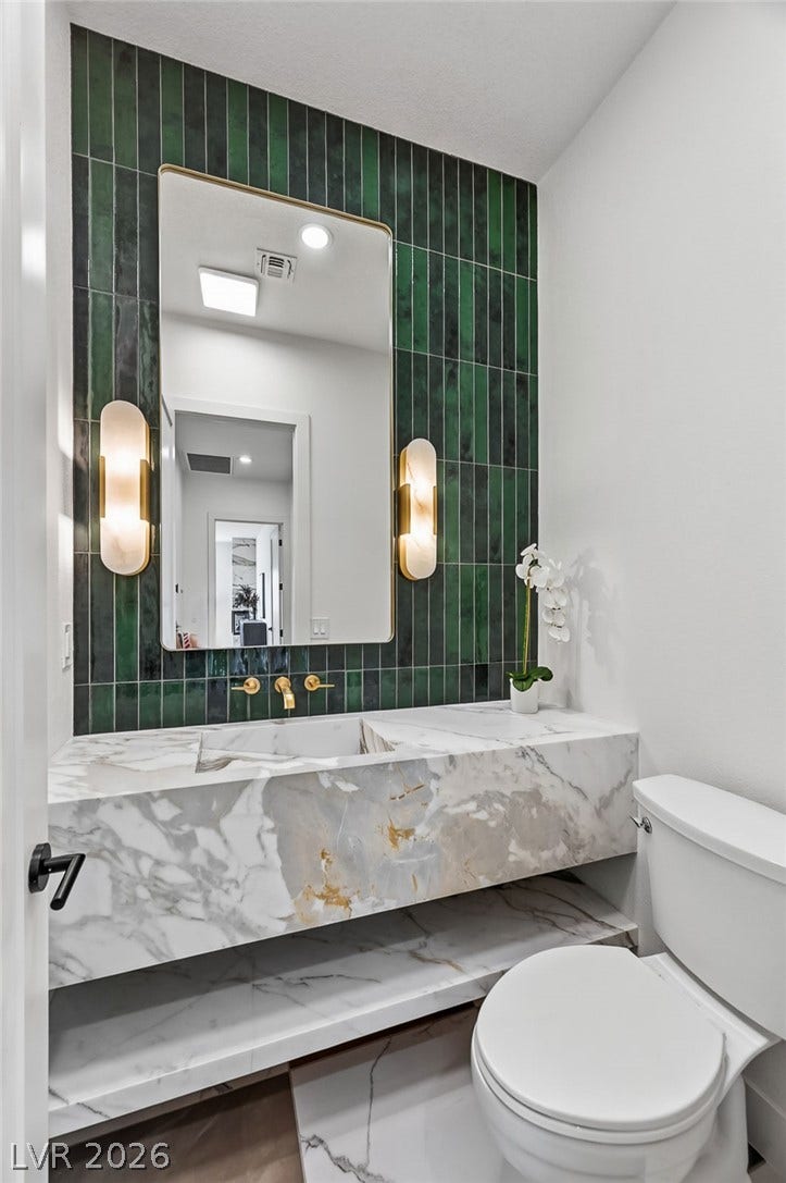 1900 Glenview Drive, Las Vegas, NV 89134 Bold vertical tiling pairs with a custom marble vanity in this striking powder room.
