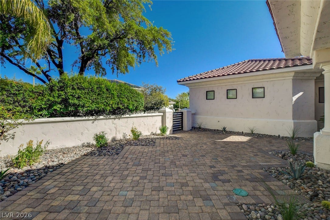 1900 Glenview Drive, Las Vegas, NV 89134 An inviting stone paver courtyard is bordered by low stucco walls under clear blue skies.