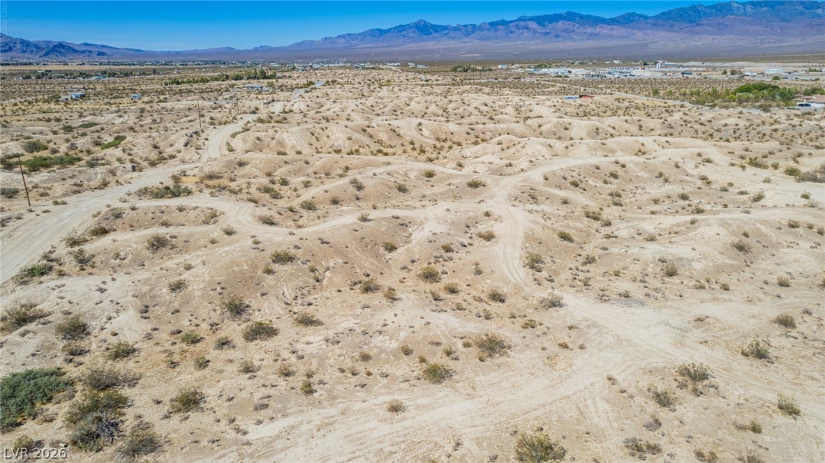1621 Rockafeller Drive, Pahrump, NV 89060 Rugged desert topography unfolds beneath a vast blue sky with distant mountain ranges.