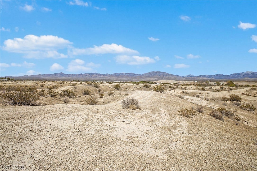 1621 Rockafeller Drive, Pahrump, NV 89060 Rugged desert terrain unfolds toward a distant mountain range under a wide blue sky.
