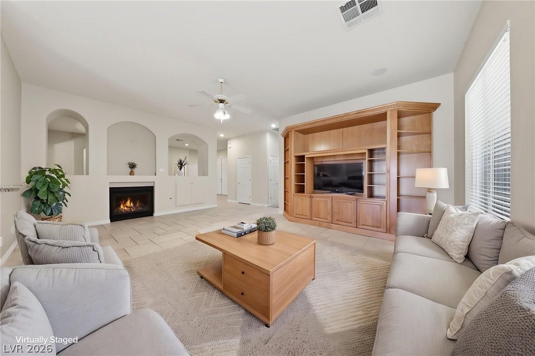 An inviting fireplace and built-in shelving anchor this spacious tile-floored living area.