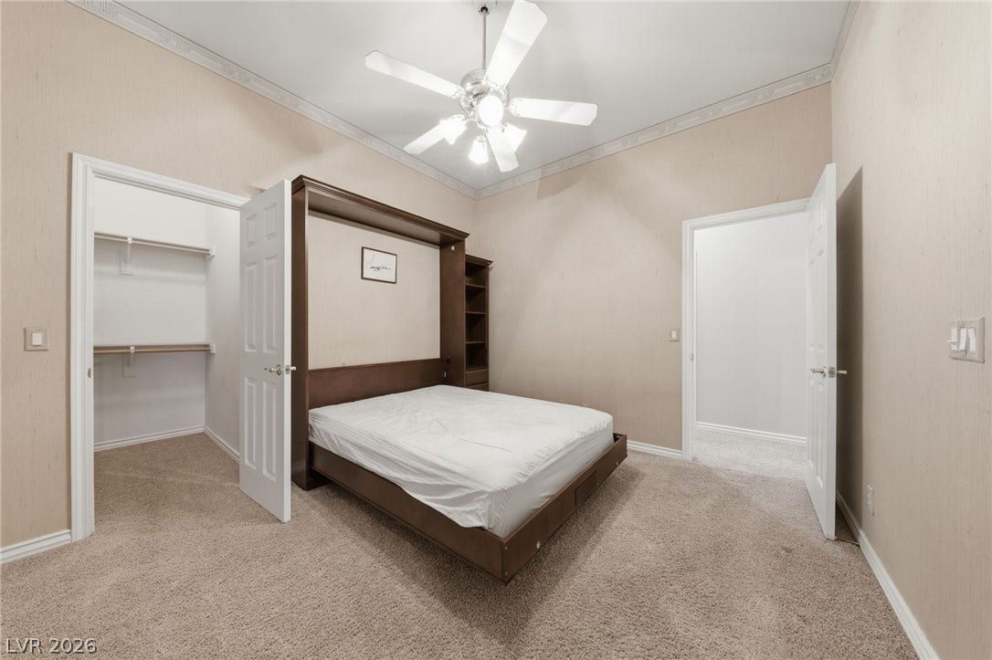 Crown molding and soft carpeting elevate this versatile room featuring a space-saving murphy bed.
