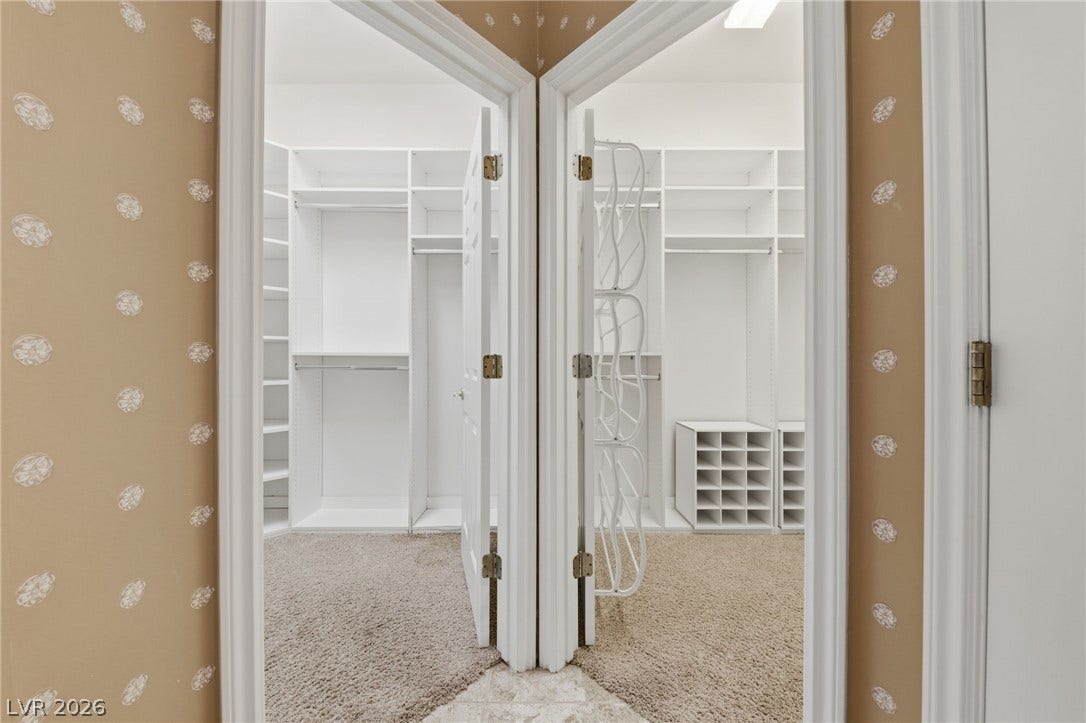 Dual entryways open to custom built-in storage solutions and soft carpeting.