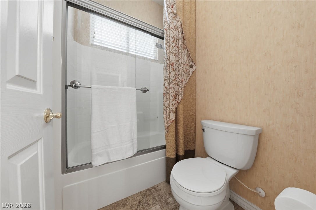 A glass-enclosed tub and shower combination anchors this guest bathroom.
